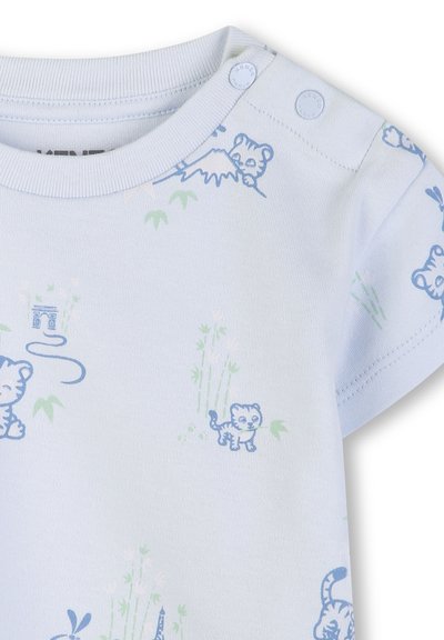 Chemise blanche pour bébé avec motifs de petits tigres bleus, de tiges de bambou vertes et d'illustrations de montagnes, équipée de boutons-pression aux épaules.
