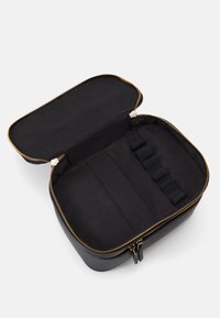 Funda con cremallera negra y exterior sólido, con una textura suave, adornos de cremallera dorada y correas elásticas en el interior para la organización.