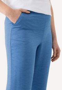 Blåa tygbyxor med en strukturerad finish, med sidofickor och en tajt passform runt midjan och låren.