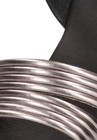 Sandalia que presenta un material negro con múltiples tiras metálicas en tonos rosa oro, texturizadas con un acabado suave, destacando un diseño minimalista.