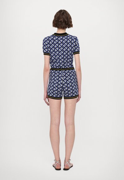 Ensemble en deux pièces avec un motif bleu marine à formes de losanges, des manches courtes et un short, agrémenté de garnitures noires et jaunes.