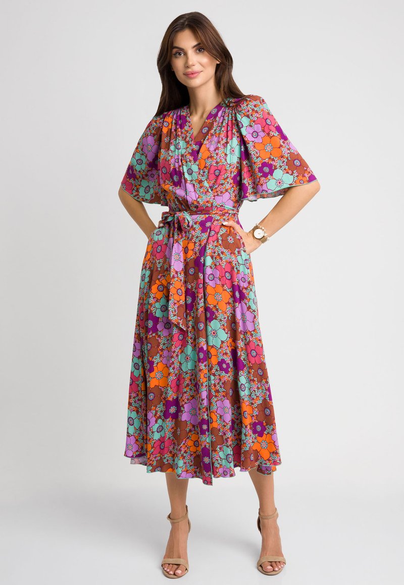 Sukienka w kwiaty z fioletowym, pomarańczowym i turkusowym kolorami, z krótkimi rękawami, paskiem w talii i długością midi. Gładka faktura materiału.