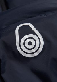 Marineblåt stof med et hvidt logo bestående af koncentriske cirkler, glat tekstur og en afrundet, abstrakt form.