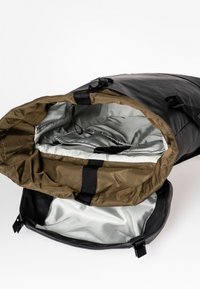 Schwarze wasserdichte Tasche mit großer Öffnung, ausgestattet mit einem olivgrünen Innenfutter und schwarzem Gurthardware; glatte und strukturierte Oberflächen sind sichtbar.