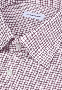 Chemise blanche à manches longues avec motif à carreaux bordeaux, boutons blancs et étiquette "seidensticker" à l'intérieur du col.