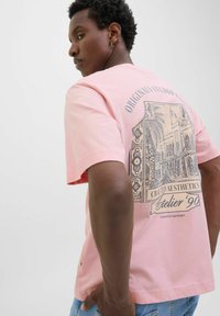Lyserød kortærmet T-shirt med et grafisk print på bagsiden, med teksten "Crafted Aesthetics" og "Atelier '90", i en afslappet pasform.