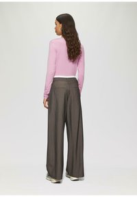 Lange mouwen roze top met een ronde hals, gecombineerd met hoge taille, wijde grijze gestreepte broek en lichte sneakers.