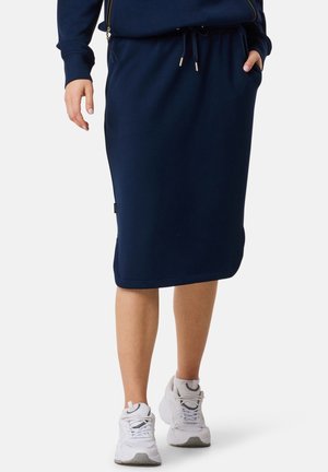 Marineblaue Midi-Rock aus weicher Stoff, mit einem elastischen Taillenbund, Zugband und seitlichen Taschen, kombiniert mit weißen Sportschuhen.