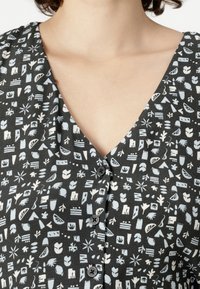 Kratka haljina s kratkim rukavima i V-izrezom, izrađena od crne tkanine ukrašene apstraktnim uzorcima u bijeloj i svijetloplavoj boji, s crnim dugmadima.