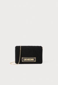 Borsa a tracolla nera in peluche con superficie texturizzata, tracolla in catena dorata e placchetta con logo dorato sul davanti. Forma rettangolare compatta.