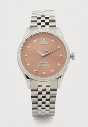 Sudraba Vivienne Westwood pulkstenis ar rozā zelta ciparnīcu, piramīdas formas stundu rādītājiem un no nerūsējošā tērauda savienotu siksniņu, kas rāda laiku 10:10:35.