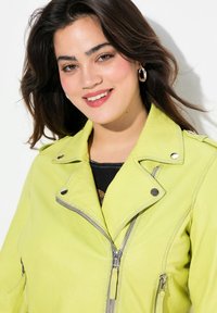 Veste de motard en cuir vert lime avec des zips et des pressions en argent. Elle dispose d'un col classique et de poches zippées à l'avant.