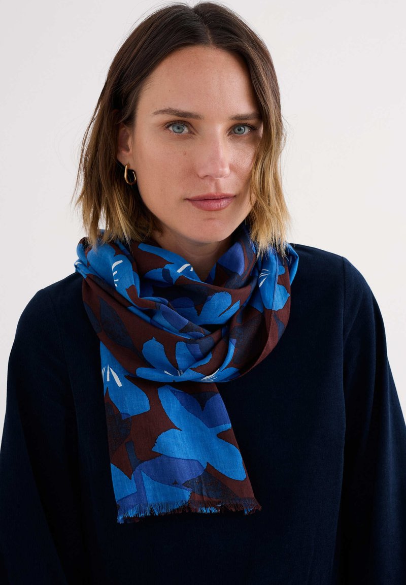 Bl scarf in Blau und Braun mit großen blauen Blüten auf einem dunkelbraunen Hintergrund, leicht und mit fransigen Kanten.