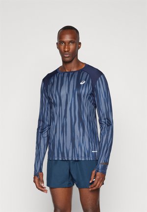 Top deportivo de manga larga en azul oscuro con rayas verticales en azul claro, con escote redondo y agujeros para los pulgares, combinado con pantalones cortos azul marino.