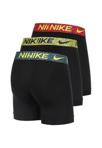 Tres calzoncillos negros de boxeador con cinturas elásticas que presentan el texto "NIKE" en rojo, amarillo y azul con un patrón texturizado.