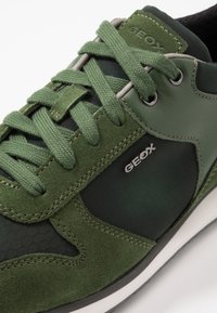 Sneaker verde realizzato in materiali scamosciati e a rete, con lacci rotondi, occhielli in metallo e suola in gomma bianca. Branding Geox sul lato.