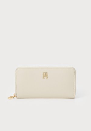 Cream leather wallet with a textured finish, gold-tone logo on the front, and a zipper closure. Compact rectangular design.