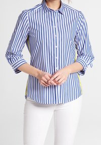 Camicia a righe blu e bianca con accenti gialli sui lati. Presenta maniche lunghe, colletto a punta e orlo curvo.