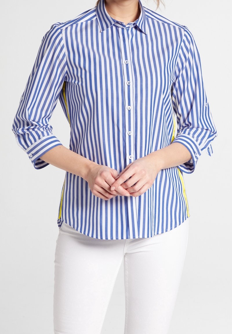 Camicia a righe blu e bianca con accenti gialli sui lati. Presenta maniche lunghe, colletto a punta e orlo curvo.