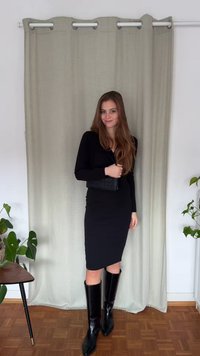 Fekete, hosszú ujjú ruha testhez simuló szabással, térdig érő fekete bőrbakanccsal és egy kis texturált borítéktáskával párosítva.