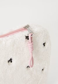White textured pouch with black accents, featuring a pink zipper and a looped pull tab. Soft, plush material with a cozy appearance.