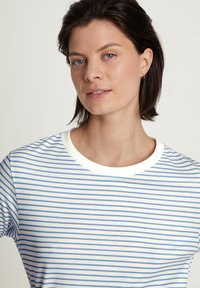 Striped t-shirt featuring blue and white lines, soft cotton material, round neckline with a white ribbed trim, fitted short sleeves.
