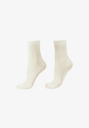 Paar weiße knöchellange Stricksocken mit vertikalen Lochmuster und gewellten Kanten auf weißem Hintergrund.