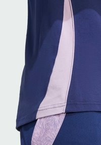 Marineblå atletisk top med en lys rosa sidestribe og teksturerede detaljer. Stoffet er glat med en tætsiddende pasform.