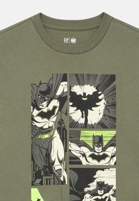 Groen katoenen T-shirt met stripverhalen van Batman in zwart-wit met groene accenten. Ronde hals, korte mouwen, comfortabele pasvorm.
