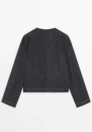 Ciemna kurtka dżinsowa z długim rękawem, o prostym kroju, bez kołnierza i widocznym przeszyciem na szwach i mankietach, widziana od tyłu.