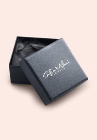 Svart texturerad smyckeslåda med en silverlogo "Sofia Milani Jewels" på locket, öppen och avslöjar skrynkligt svart silkepapper inuti.