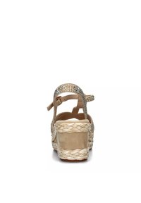 Sandalias de plataforma beige con suela de yute trenzado, tacón texturizado y una tira decorativa con brillantes transparentes.