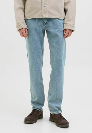 Jeans din denim albastre deschise cu croi drept, prezentând o decolorare subtilă, design cu cinci buzunare și pantofi eleganți maro uzati.