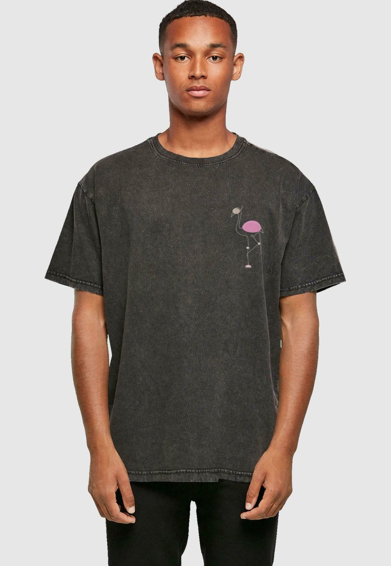 Camiseta de denim negro de manga corta, con un gráfico de flamenco rosa en la zona del pecho izquierdo y un diseño clásico de cuello redondo.