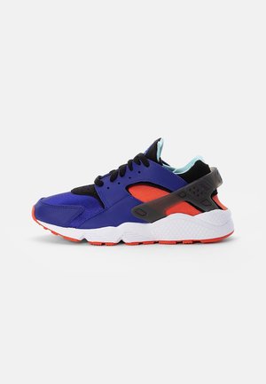 Basket athlétique bleue, noire et rouge avec semelle blanche, sangle de talon noire, lacets noirs et doublure intérieure bleu clair vue de côté gauche.