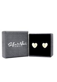 Orecchini a forma di cuore in oro con design a pezzo di puzzle, esposti in una scatola grigia foderata in velluto nero contrassegnata "Sofia Milani Jewels."