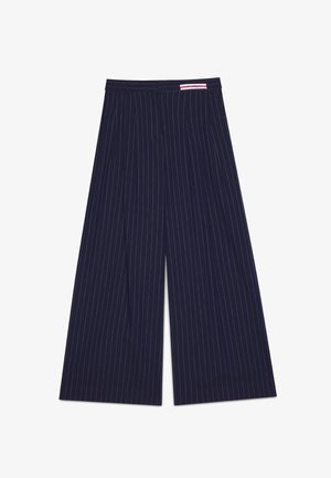 Marineblaue Hosen mit weitem Bein, weißen Nadelstreifen und einem kleinen roten und weißen Etikett am Bund.