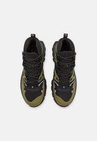 Chaussures de randonnée noires et vert olive avec une tige texturée, une semelle épaisse, un embout renforcé et un système de laçage complexe. Comprend une languette.