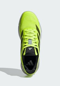 Chaussure de sport jaune vif avec des bandes noires, une semelle blanche, des lacets, et le logo Adidas sur la languette et la semelle intérieure sur un fond clair.