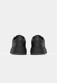 Zapatillas negras con parte superior de cuero suave, punta redonda y suela de goma. Presentan un diseño minimalista y un logotipo sutil en el talón.