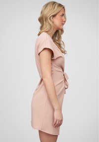 Light pink dress, fitted silhouette, short sleeves, gathered side detail with a bow, smooth fabric, knee-length, minimalistic design.