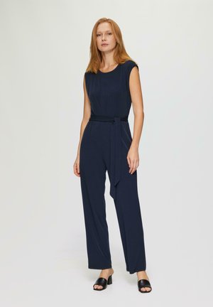 Marineblauwe jumpsuit met een aangesloten taille en een wijde pijpenontwerp. Voorzien van een ronde halslijn en een stoffen riem als accent. Glad textuur.