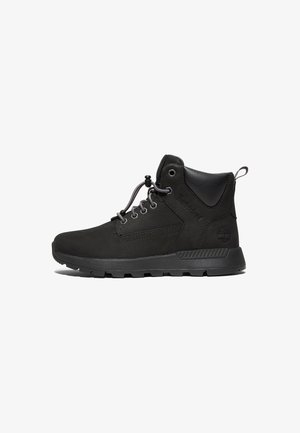 Bota Timberland negra de media caña con cuello acolchado, cierre con cordones y tirador, y suela resistente, mostrada de perfil sobre fondo blanco.