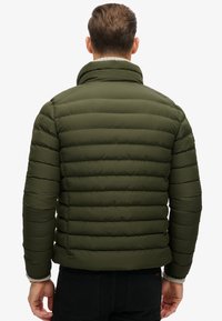 Oliven grøn pufferjakke med horisontale syninger, høj krave og ribbede manchetter. Letvægtsmateriale, afslappet design, set fra ryggen.