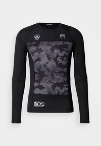 Czarna, długorękawowa, kompresyjna koszulka z panelem frontowym w kamuflażowy wzór, teksturowanymi rękawami oraz logo na ramionach.