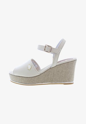 Weiße Keilsandalen mit einer strukturierten beigefarbenen Plattform, verstellbarem Knöchelriemen mit einer silbernen Schnalle und einem kleinen bestickten Detail auf dem Obermaterial.