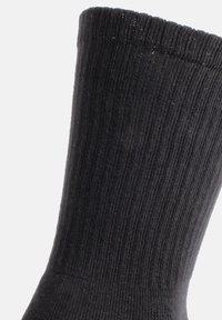 Calcetín negro acanalado con un borde superior elástico, fabricado en un tejido suave, que presenta una textura lisa y uniforme, además de una forma ajustada.