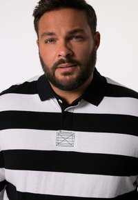 Mustikka- ja valkooraita polo-paita, jossa on musta kauluskäänne ja pieni brodeerattu logo rinnassa. Puuvillamateriaali, jossa on sileä tekstuuri.