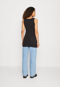 Black sleeveless top with a round neckline, paired with light blue wide-leg jeans and black footwear. Smooth texture, casual fit.