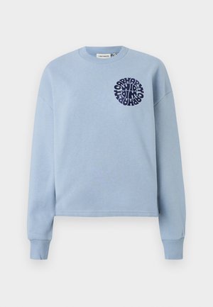 Vaaleansininen puuvillaneule, jossa on pitkät hihat ja pyöreä pääntie. Vasemmassa rinnassa on tummansininen pyöreä graafinen kuvio. Pehmeä rakenne.